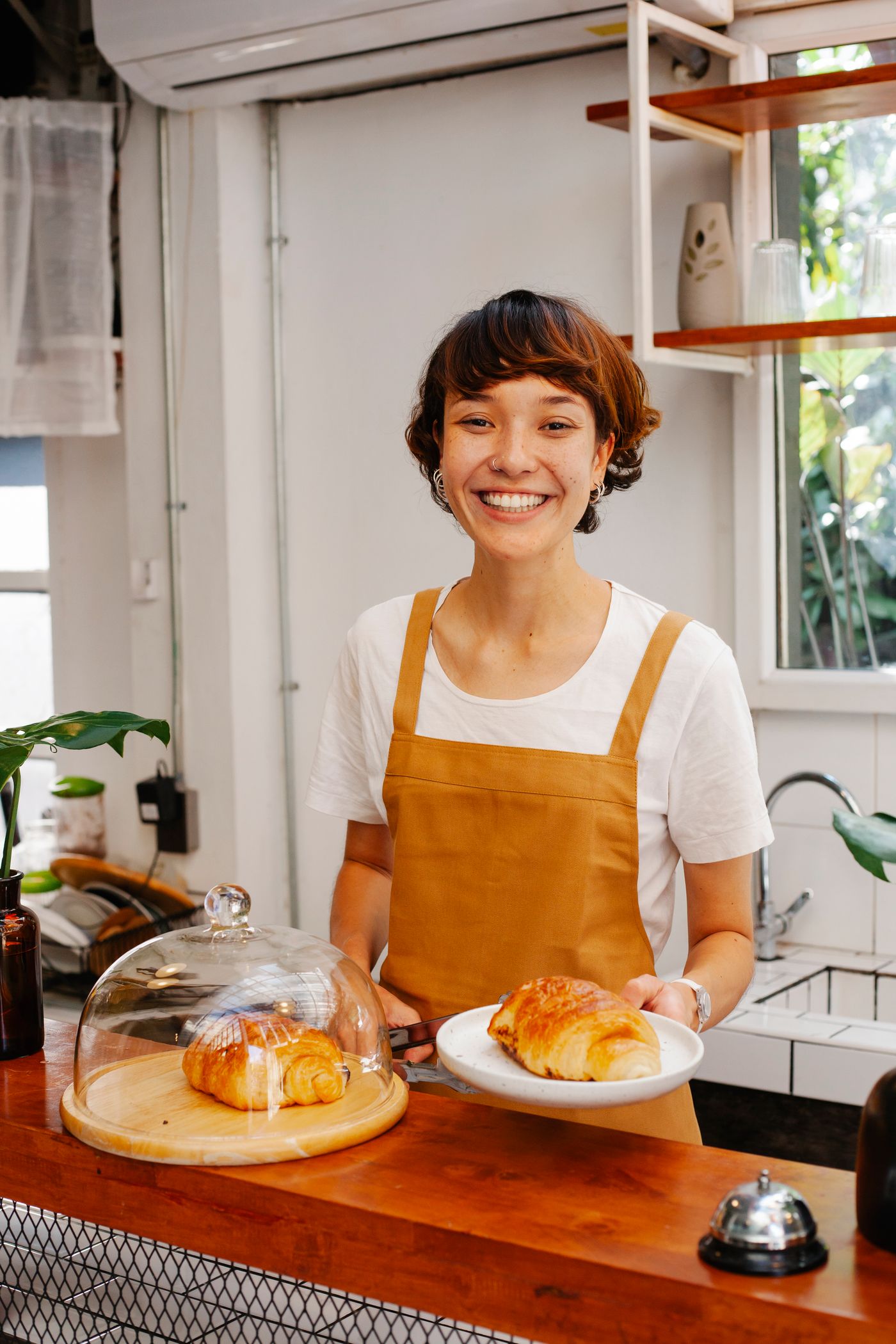 A smiling bakery owner serving fresh pastries at her counter